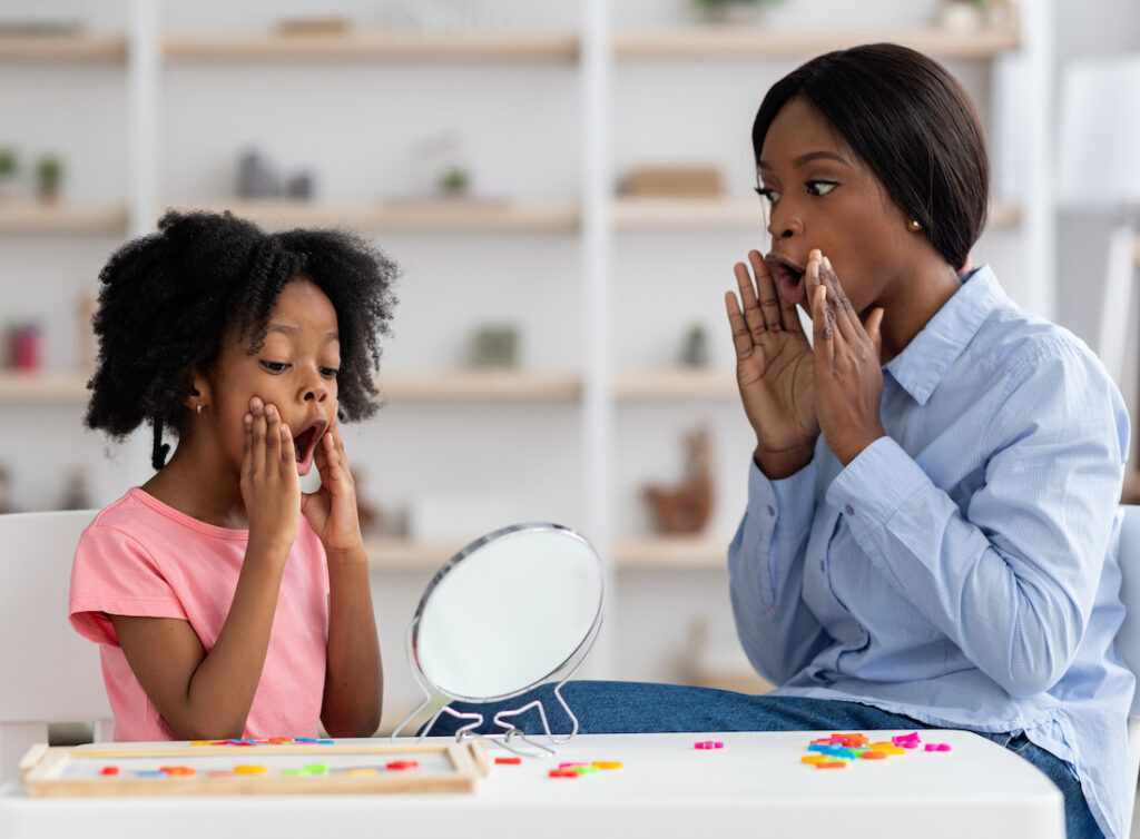 Female speech language pathologist exercising with adorable little girl Female speech language pathologist exercising with adorable little girl