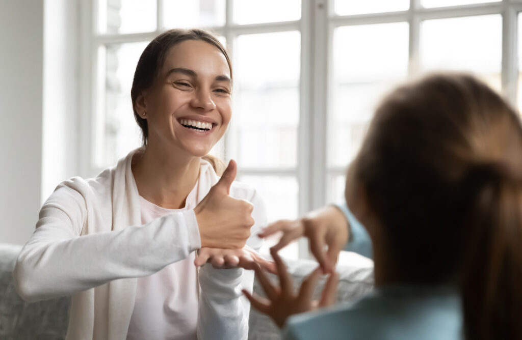 Smiling Caucasian woman learn sign language with little kid Smiling Caucasian woman learn sign language with little kid