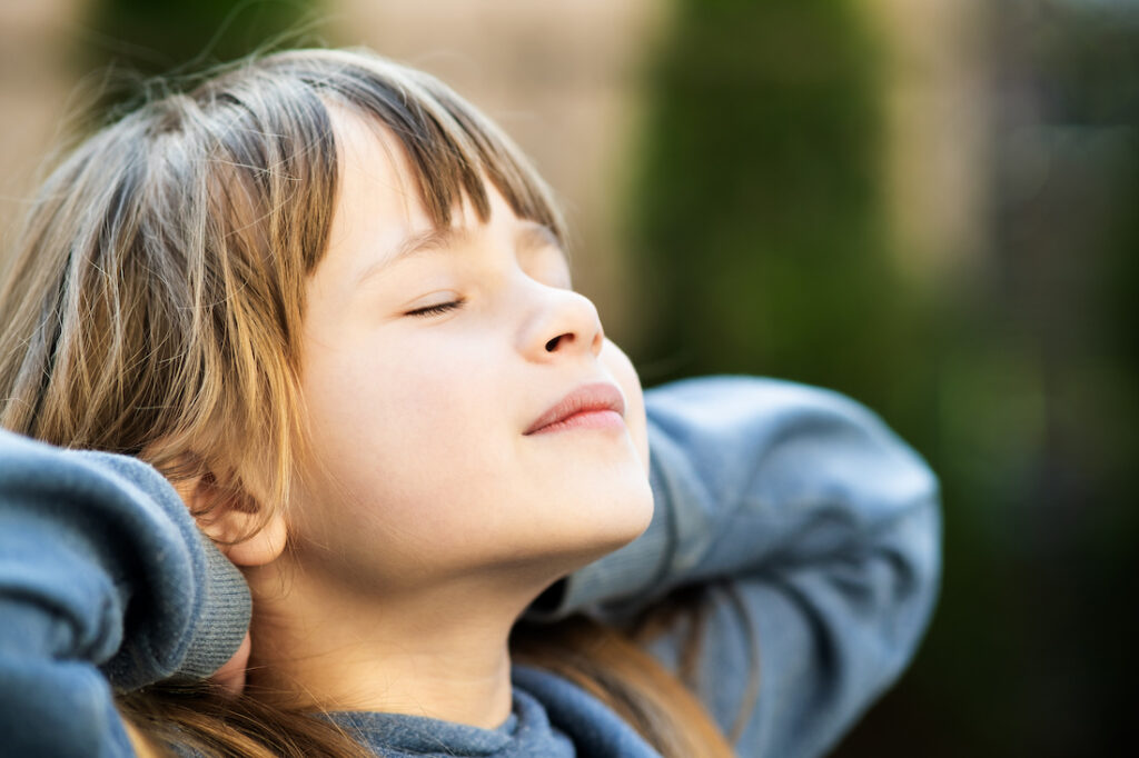 Portrait of young pretty child girl with long hair enjoying warm sunny day in summer outdoors. Cute female kid relaxing on fresh air outside. Portrait of young pretty child girl with long hair enjoying warm sunny day in summer outdoors. Cute female kid relaxing on fresh air outside.