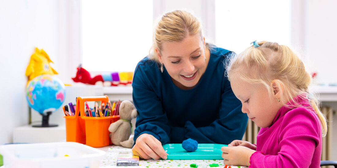 Toddler girl in child occupational therapy session doing sensory playful exercises with her therapist. Toddler girl in child occupational therapy session doing sensory playful exercises with her therapist.